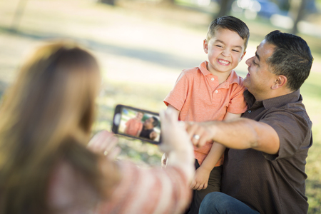 Happy Mixed Race Family Taking A Phone Camera Picture At The Park.の写真素材