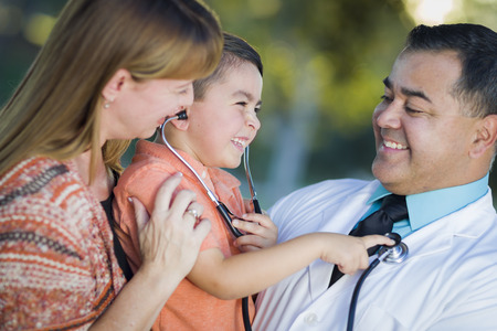 Happy Mixed Race Boy, Mother and Hispanic Doctor Having Fun With Stethoscope Outdoors.の写真素材