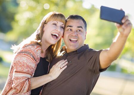 Attractive Mixed Race Couple Taking Self Portraits in the Park.の写真素材