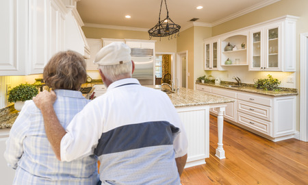 Happy Senior Couple Looking Over Beautiful Custom Kitchen Design.の写真素材