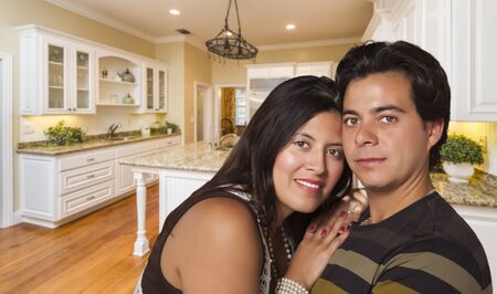 Affectionate Hispanic Couple Inside Custom Kitchen Interior.の写真素材