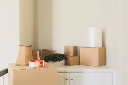 Variety of Packed Moving Boxes and Materials In Empty Room.