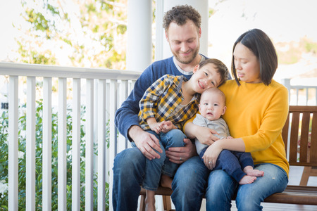 Young Mixed Race Chinese and Caucasian Family Portrait On Their Front Porch.の写真素材