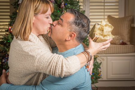 Happy Young Mixed Race Couple with Present Near Christmas Tree.の写真素材
