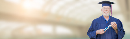 Banner with Proud Senior Adult Man Graduate In Cap and Gown Holding Diploma Inside School Building.の写真素材