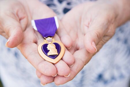 Senior Woman Holding The Military Purple Heart Medal In Her Hands.の写真素材