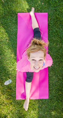 Overhead of Young Fit Flexible Adult Woman Outdoors on The Grass With Yoga Mat Doing The Splits.の写真素材