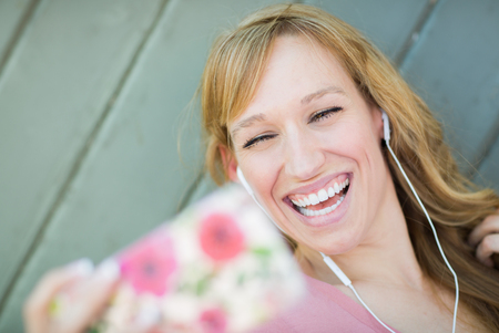 Young Adult Woman Wearing Earphones Taking a Selfie with Her Smart Phone.の写真素材