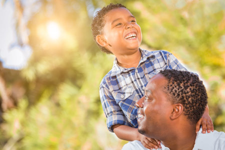 Mixed Race Son and African American Father Playing Outdoors Together.の写真素材