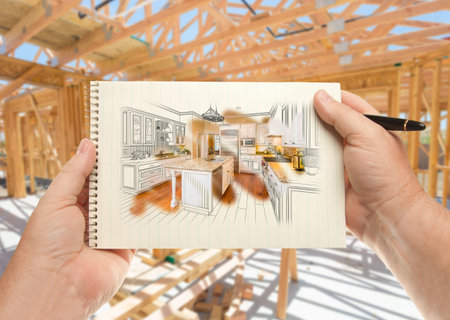 Male hands holding pen and pad of paper with custom kitchen illustration inside construction...