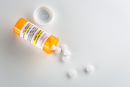 Non-Proprietary Medicine Prescription Bottle and Spilled Pills  Over Head on Grey Background.の写真素材