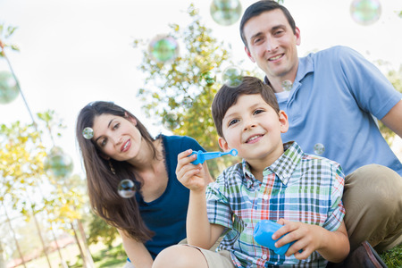 Young Boy Blowing Bubbles with His Parents in the Park.の写真素材