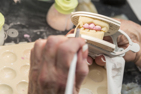 Female Dental Technician Applying Porcelain To A 3D Printed Implant Mold In The Lab.の写真素材