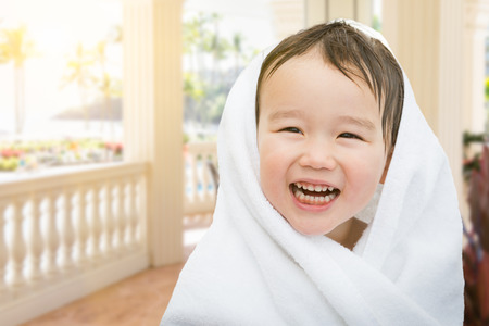 Happy Cute Mixed Race Chinese and Caucasian Boy On Tropical Patio Wrapped In A Towel.の写真素材