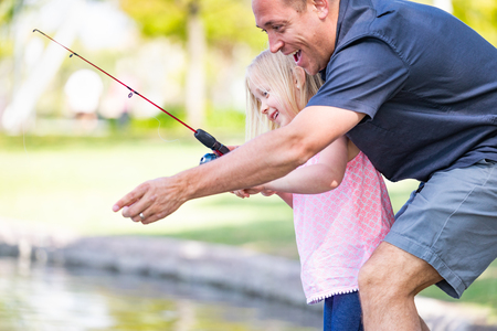 Young Caucasian Father and Daughter Having Fun Fishing At The Lake.の写真素材