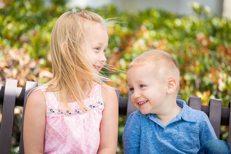 Young Sister and Brother Having Fun On The Bench At The Park.の写真素材