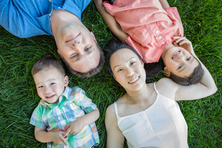 Chinese Mother, Caucasian Father and Mixed Race Children Laying On Grass.の写真素材