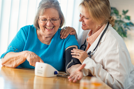 Senior Adult Woman Learning From Female Doctor to Use Blood Pressure Machine.の写真素材