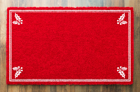 Blank Holiday Red Welcome Mat With Holly Corners On Wood Floor Background.の写真素材