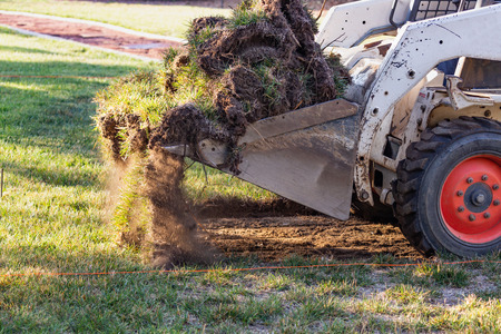 Small Bulldozer Removing Grass From Yard Preparing For Pool Installationの写真素材