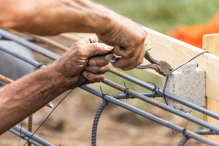 Worker Securing Steel Rebar Framing With Wire Plier Cutter Tool At Construction Site.の写真素材
