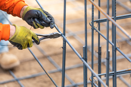Worker Securing Steel Rebar Framing With Wire Plier Cutter Tool At Construction Site.の写真素材