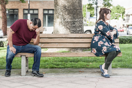 Unhappy Mixed Race Couple Sitting Facing Away From Each Other on Park Bench.の写真素材
