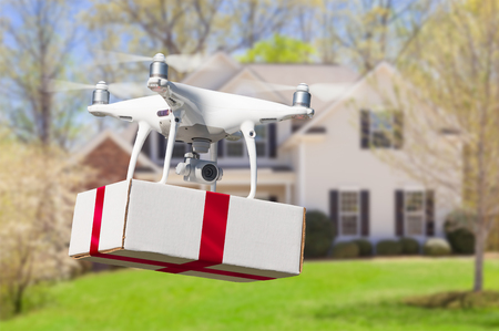 Unmanned Aircraft System (UAV) Quadcopter Drone Delivering Box With Red Ribbon To Homeの写真素材