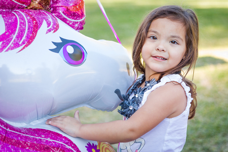 Cute Young Mixed Race Baby Girl Holding Mylar Balloon Outdoors.の写真素材