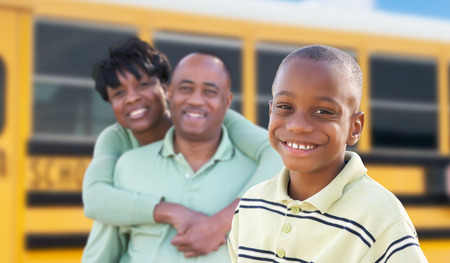 Proud African American Parents and Young Boy Near School Bus.の写真素材