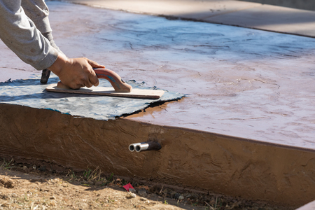 Construction Worker Applying Pressure to Texture Template On Wet Cementの写真素材