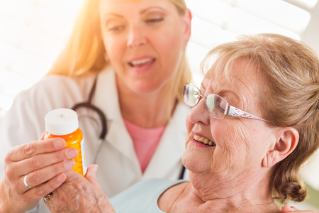 Happy Female Doctor or Nurse Explaining Prescription to Senior Adult Woman.の写真素材