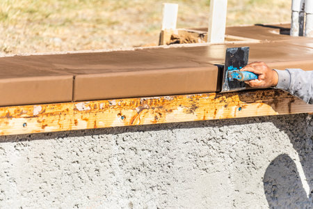 Construction Worker Using Stainless Steel Edger On Wet Cement Forming Coping Around New Pool.