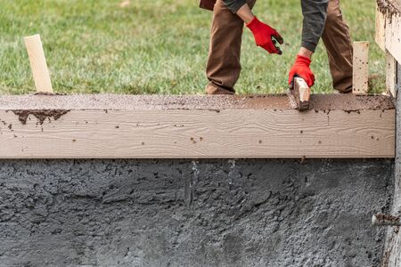 Construction Worker Leveling Wet Cement Into Wood Framing.の写真素材