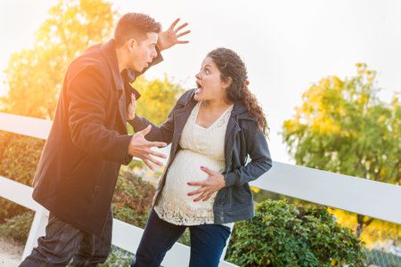 Stunned Hispanic Pregnant Young Couple In Pain Walking Outdoors.