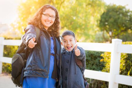 Hispanic Brother and Sister Wearing Backpacks With Thumbs Up.の写真素材