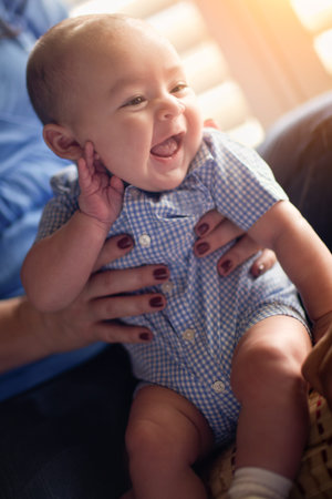 Happy Mixed Race Couple Enjoying Their Newborn Son In The Light of The Window.