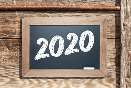 2020 Written on Slate Chalk Board Against Aged Wood and Pipe Background.