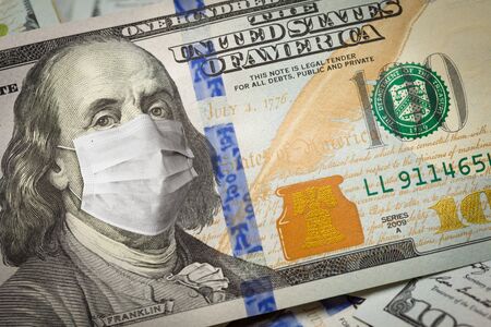 One Hundred Dollar Bill With Medical Face Mask on Face of Benjamin Franklin.の写真素材