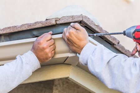 Workers Attaching Aluminum Rain Gutter to Fascia of House.の写真素材
