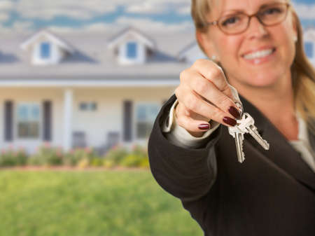 Real Estate Agent Handing Over New House Keys with House Behind.の写真素材