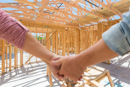 Couple Holding Hands Looking At Their New House Framing Under Construction.の写真素材