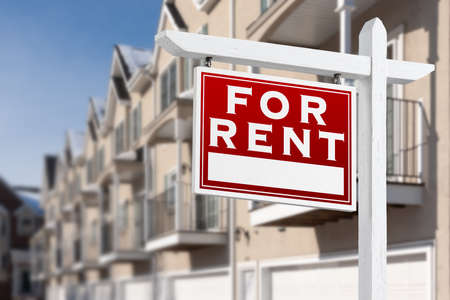 For Rent Real Estate Sign In Front of a Row of Apartment Condominiums Balconies and Garage Doors.の写真素材