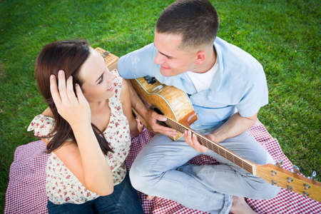 Young Adult Man Playing Guitar for His Girlfriend in the Park.の写真素材