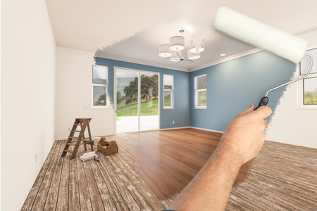 Before and After of Man Painting Roller to Reveal Newly Remodeled Room with Fresh Blue Paint and New Floors.の写真素材