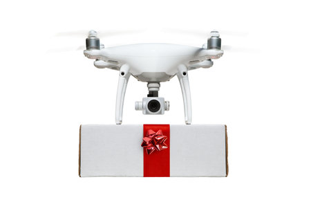 Unmanned UAV Drone Quadcopter Delivering  A Package with a Red Ribbon and Bow Isolated on a White Background.の写真素材