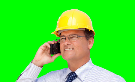 Engineer or Contractor Wearing Hard Hat and Necktie Talks on His Cell Phone Over A Green Screen.の写真素材
