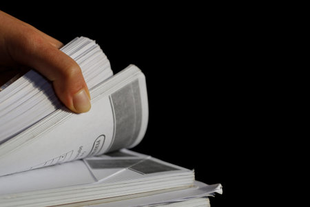 The human hand is flipping through the pages of printing out.
