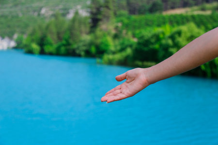 The woman hand point at blue lake in Turkey.