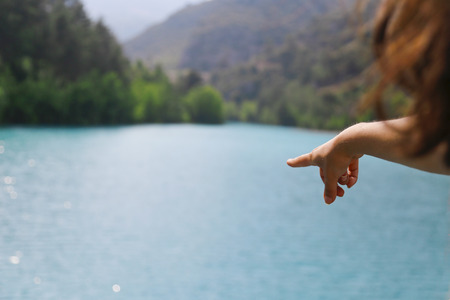 The woman hand point at blue lake in Turkey.の写真素材